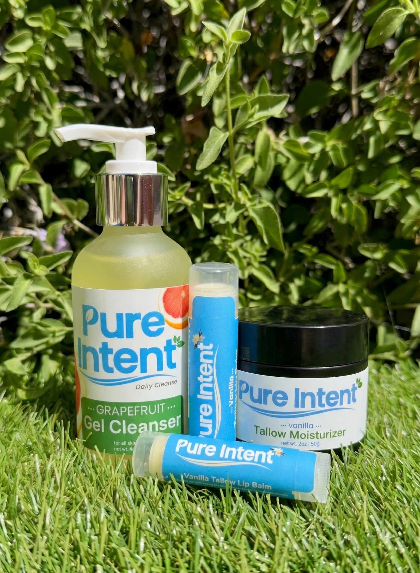 Pure Intent skincare products on grass with greenery in the background